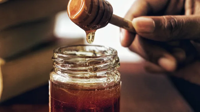 A jar of honey with a honey spoon.