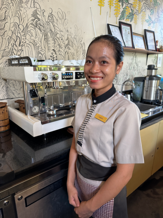 Tongoul poses in front of an espresso machine.