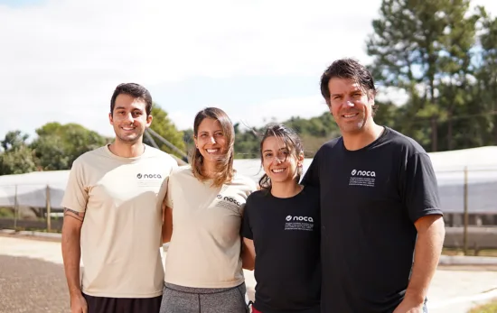 Four people gathered for a photo in front of drying beds.