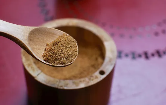 A wooden spoon with coconut sugar in the bowl. The sugar is a light brown color.