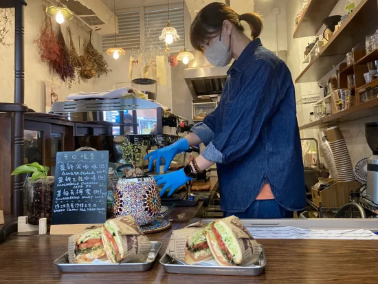 Two sandwiches on the counter at Good day with a barista behind the bar.