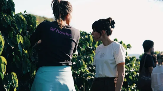 Two women looking at coffee trees, one in a Flowins t shirt.