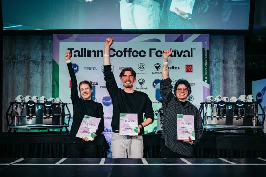 Three baristas pose with one fist raised above their heads in victory.