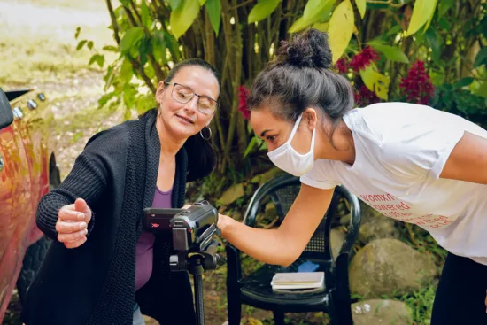 Two women look at a video camera.