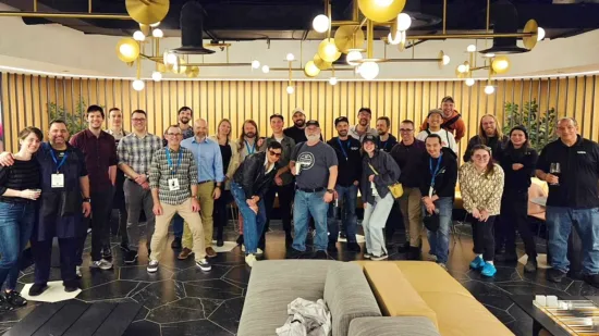 A large group of people gathers for a photo of the Coffee technicians Guild meet-up in a fancy room.