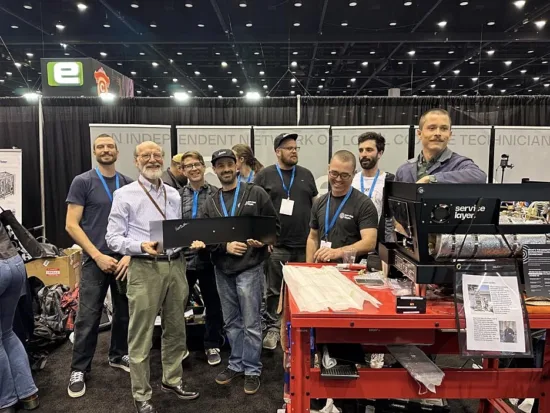 A line of techs hold up a signed piece of the newly-built Service Layer Linea machine.