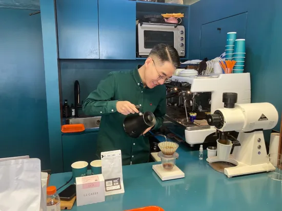 A man pours water into a pour over with a goose neck kettle. 