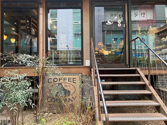 The front entrance to Fritz has stairs leading up to a glassed in front room, and a wooden sign outside with their cute seal (the animal) holding a coffee cup.