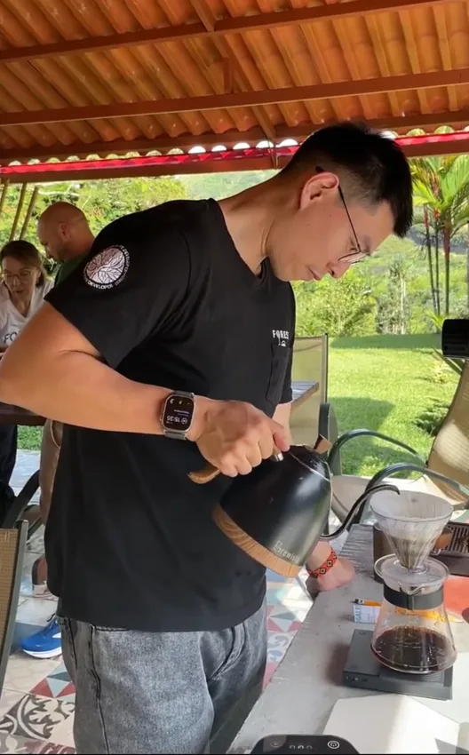 Weihong brewing a pourover outside under a canopy.