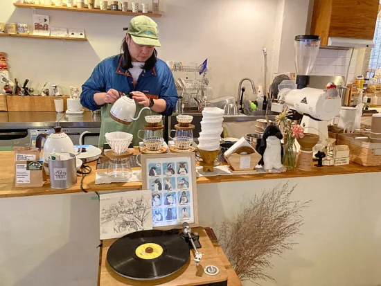 In front of Lazy's bar is a record player, while penguin paraphernalia and white coffee brewers and grinder cover the counter.