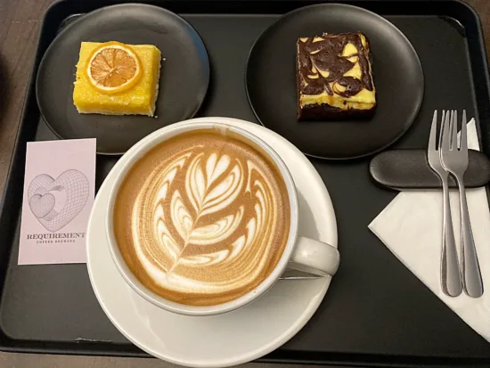 Latte and snack cakes on a black tray.