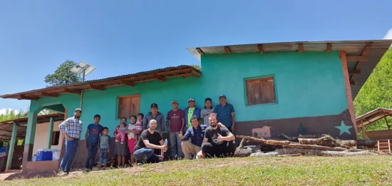 Nikola poses with producers and family outside a blue house.