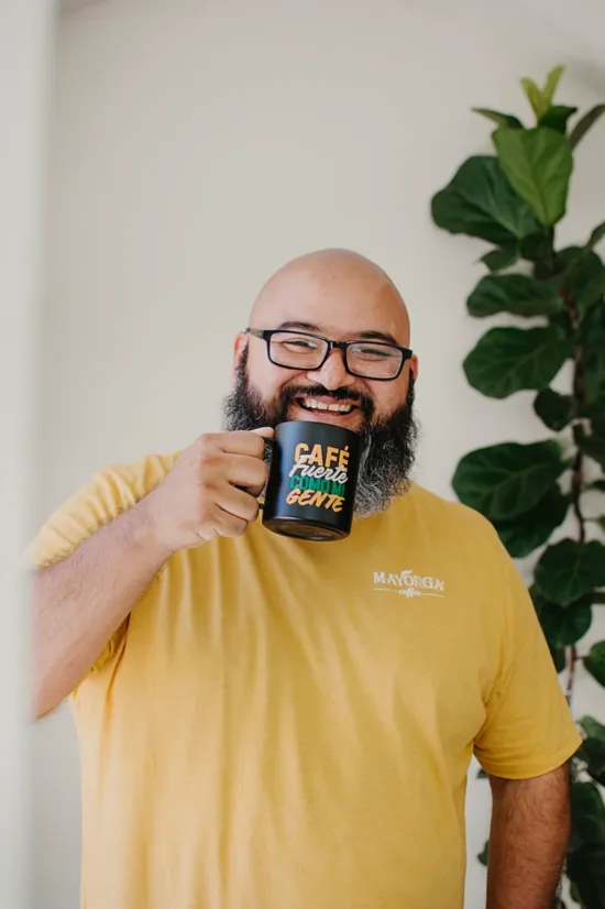 Eduardo with a black mug, standing in front of a fig tree.