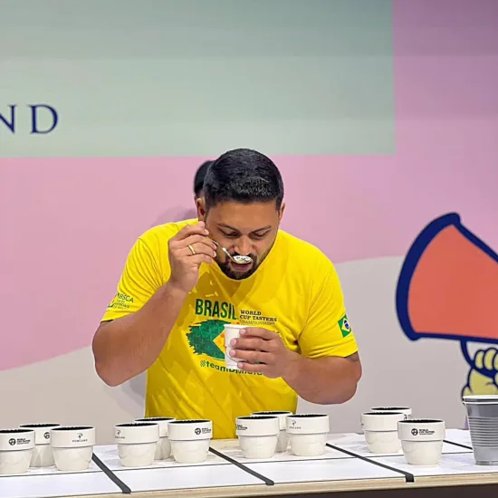 Dionatan slurps coffee on the tasting table with a cupping spoon.