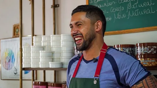 Dionatan laughs. He wears an apron. You can see part of a tattoo on his arm.