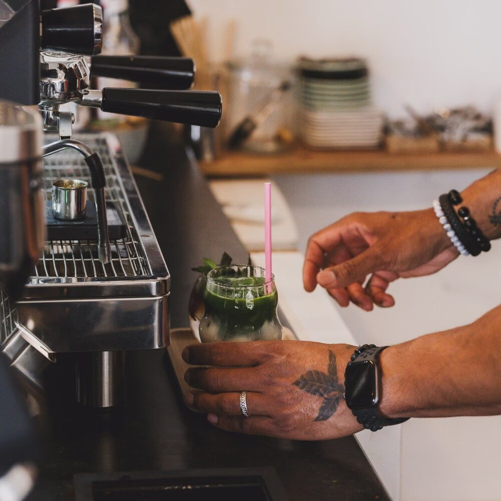 Un barista sostiene un vaso lleno de una bebida helada Matcha.